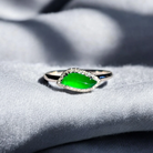 White gold ring with a jade stone on a textured gray surface