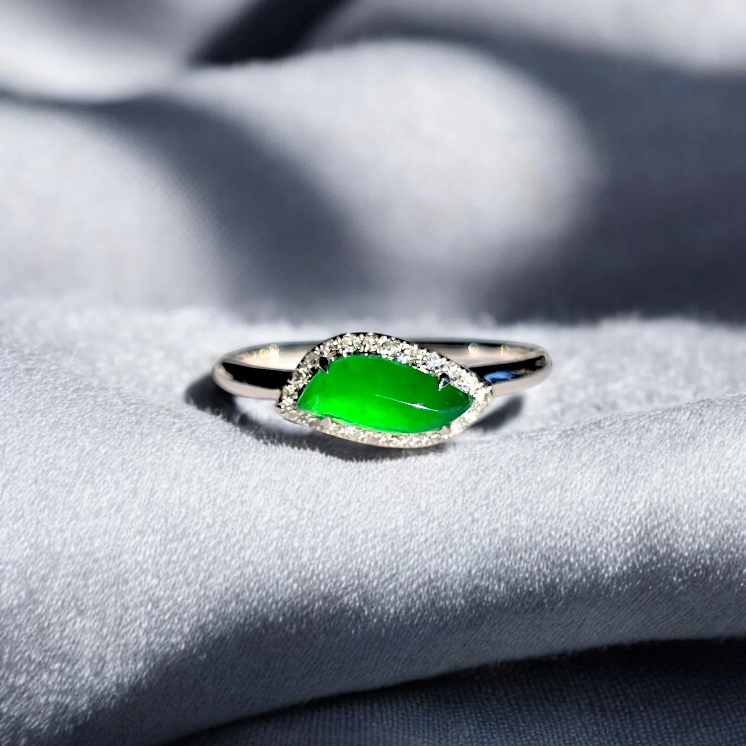 White gold ring with a jade stone on a textured gray surface