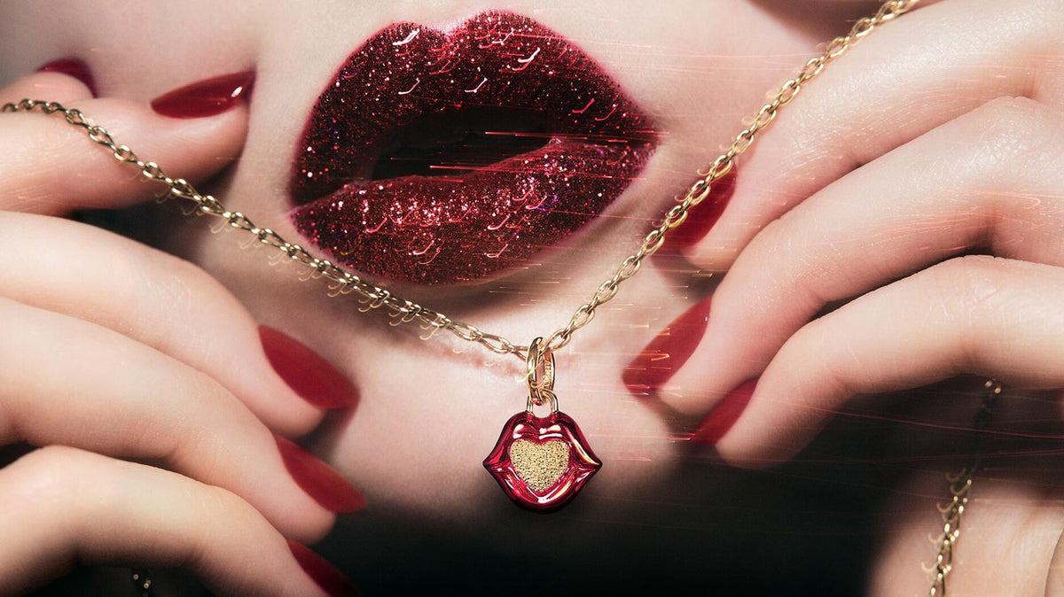 Pandora x Pat McGrath lip pendant held against red glitter lips