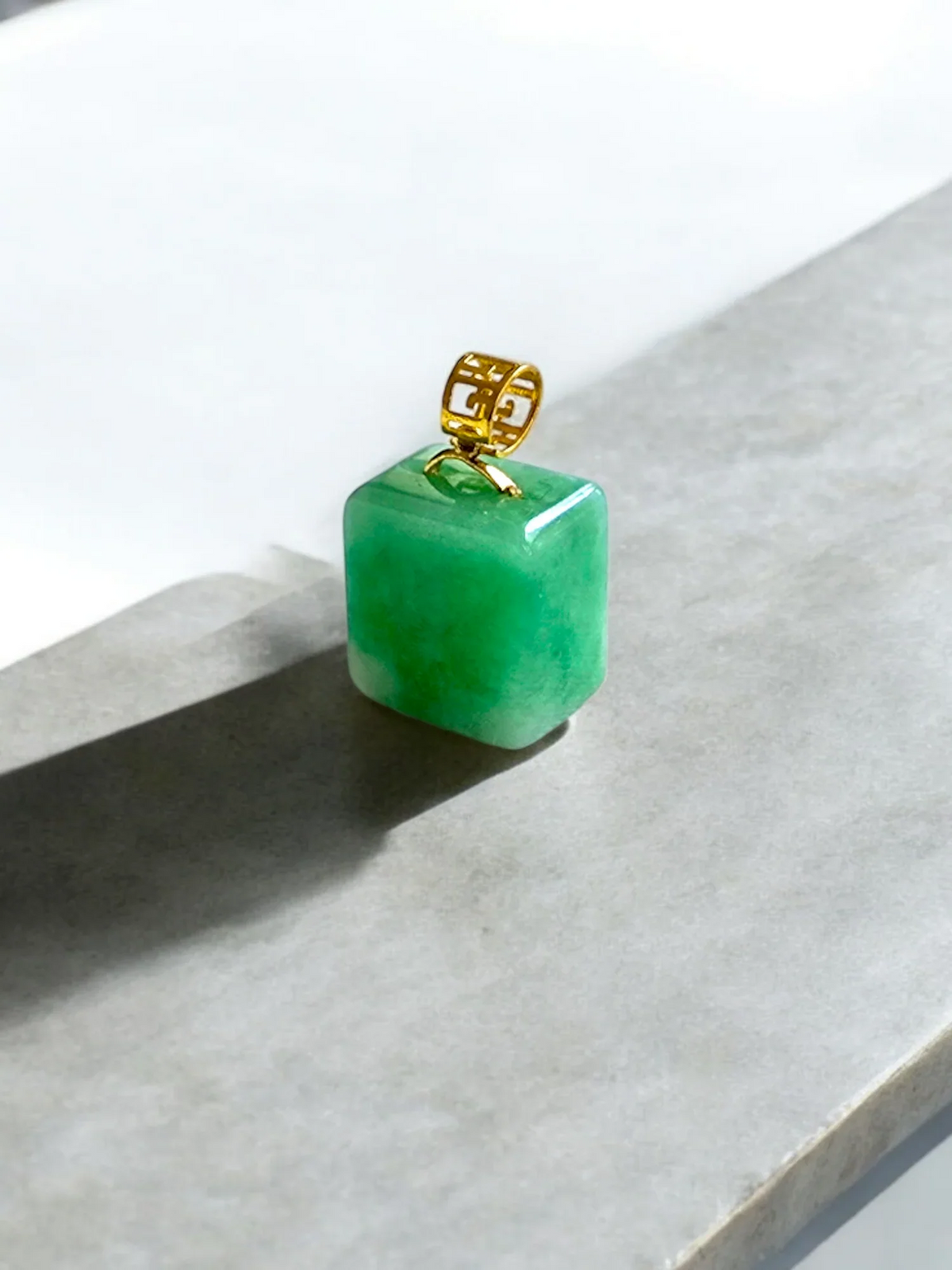 Green jade cube pendant with a gold bail