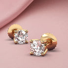 14k yellow gold diamond stud earrings featuring brilliant-cut diamonds with a total of .70 carats (each stud .35 carats). Displayed against a soft pink background, highlighting their elegance and sparkle.